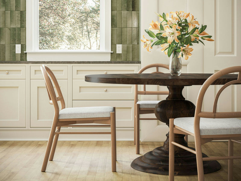 A close-up of the Josephine Round Dining Table - Tobacco from James+James showcases a wooden surface with dark brown and lighter brown grain patterns. The texture reveals natural lines, knots, and color variations, giving the table a rich, rustic appearance. The intricate details highlight the organic beauty of the wood.