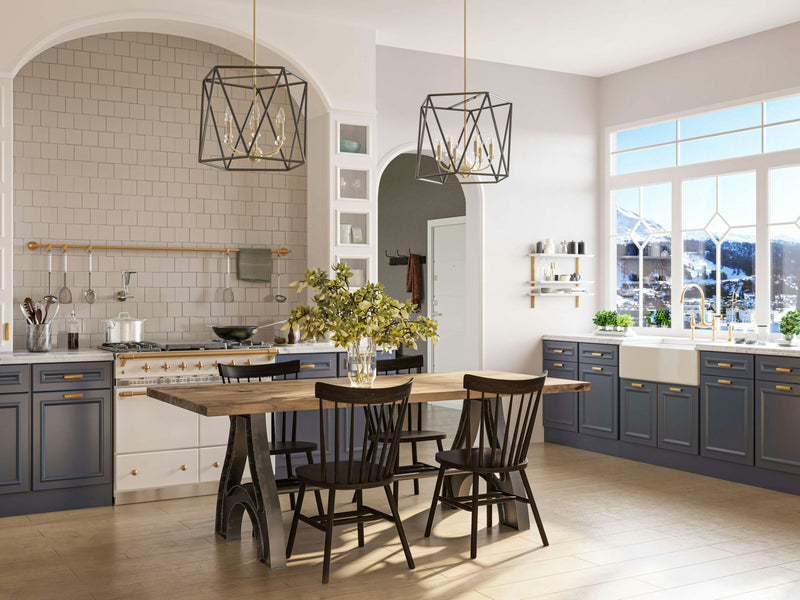 A spacious, modern kitchen with gray lower cabinets and white upper cabinets. The Wishbone Dining Table - Harvest Wheat from James+James, accompanied by black chairs, is centered under geometric pendant lights. Large windows offer a view of snow-capped mountains and let in natural light, brightening the space.