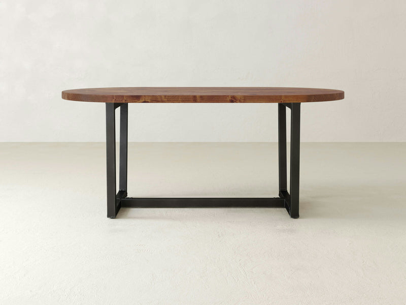 A contemporary Trapezoid Oval Dining Table - Tuscany from James+James showcases a rectangular wooden top in a rich dark brown hue, rounded edges, and sturdy black metal legs in a double pedestal design, all set against a minimalist white background.