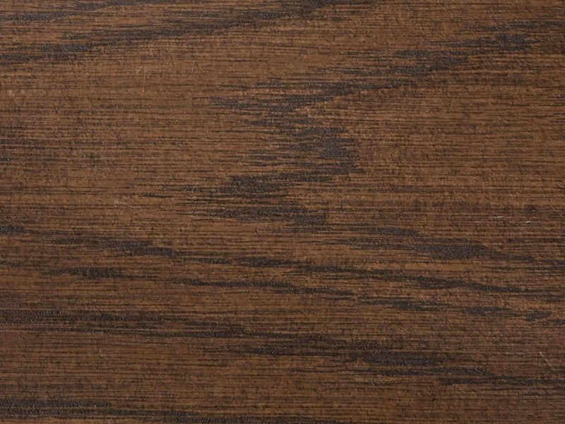 A close-up of the Deep Grey on White Oak Sample from James+James reveals a captivating wooden surface with a visible grain pattern. The wood displays a deep and rich grey color with streaks of lighter and darker shades, showcasing its natural texture and variation that imbues it with a rustic, authentic appearance.