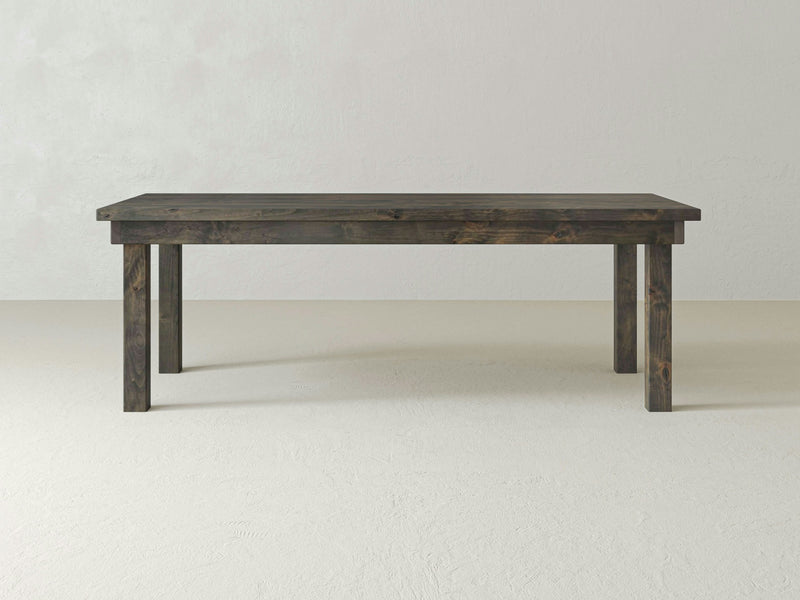 A rectangular Farmhouse Dining Table - Deep Grey by James+James with sturdy legs is set against a plain, light-colored background. The table features a simple, minimalist design with no additional items or decorations present.