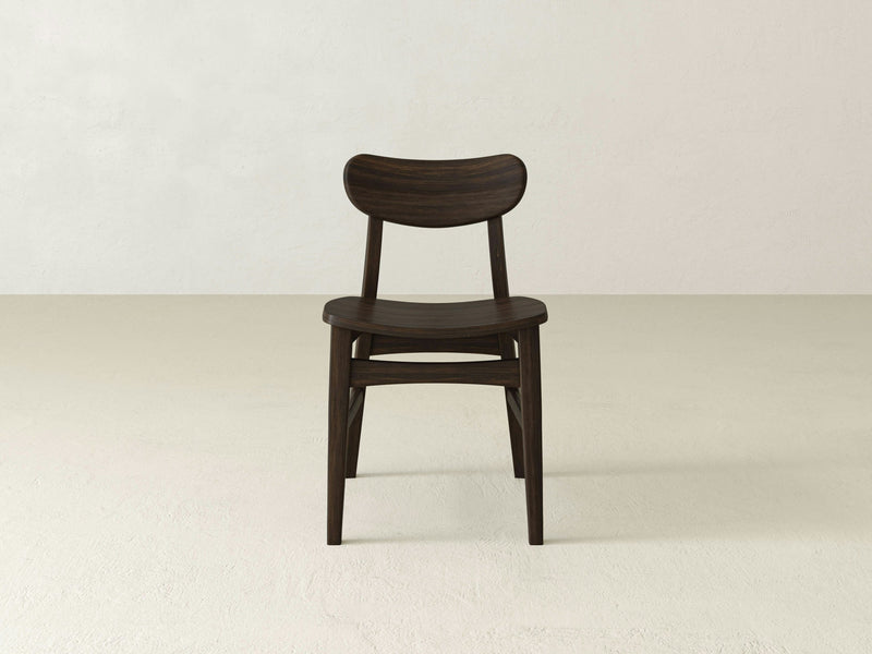 The Lynn Dining Chair - Tobacco by James+James features a curved backrest and seat with a dark brown finish. It has four straight legs and is positioned against a plain, light-colored background. The chair's simple and minimalist design accentuates the natural wood grain and its smooth, polished surface.