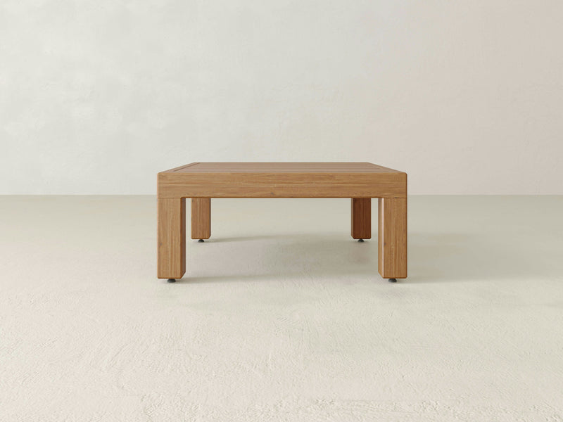 Introducing the **Aria Outdoor Coffee Table** by **James+James**: a simplistic wooden coffee table with a light finish, perfect for your outdoor space. Its rectangular shape and straight, sturdy legs are designed to complement minimalist rooms featuring light-colored walls and floors. The overall aesthetic is clean and modern, making it an ideal addition to sophisticated outdoor living areas.