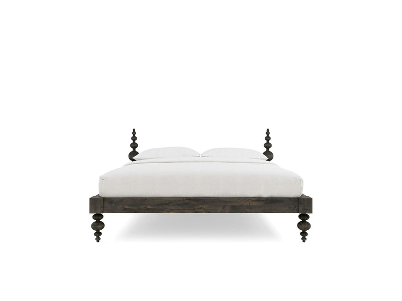 A front-facing view of the Ophelia Bed in deep grey by James+James, featuring four decorative turned posts. The bed is dressed in white bedding with two pillows. The overall design is simple and elegant, emphasizing the classic look of the turned wood against a plain white background.