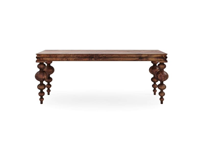 The Olivia Sofa Table - Tuscany by James+James is a rectangular wooden table featuring a dark finish and intricately turned legs. Its rustic, antique-style design stands on four sturdy legs adorned with ornamental carvings, while the tabletop boasts a smooth, polished surface.