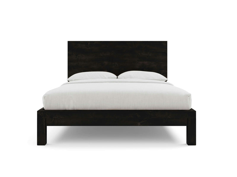 A front view of the Sawyer Bed - Charred Ember by James+James showcases its minimalistic black wooden frame. The bed is meticulously made with white linens, featuring two pillows resting against a tall, rectangular headboard. The plain white background accentuates the bed's clean and elegant design.