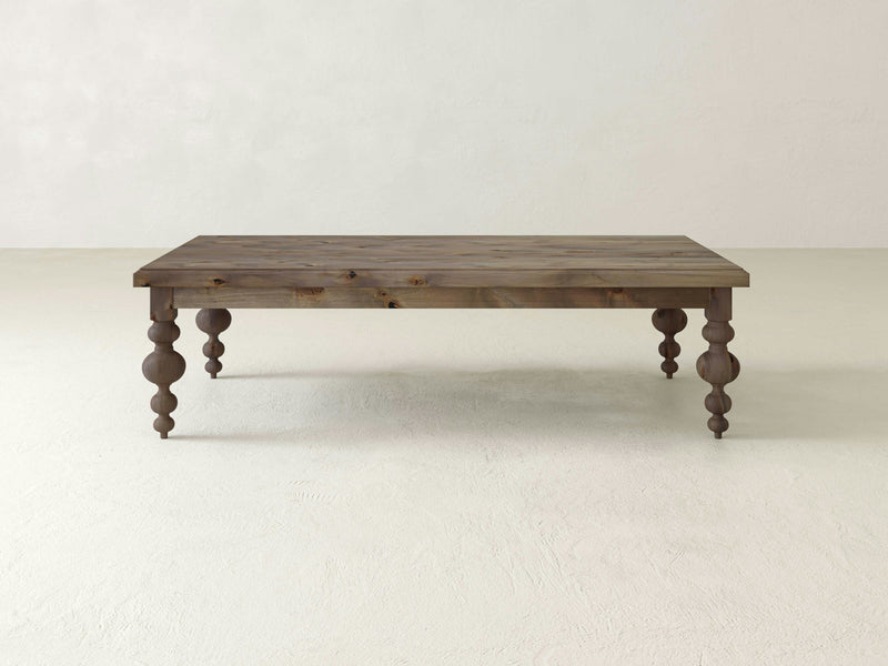 The Olivia Coffee Table by James+James, featuring a barn wood finish and sturdy legs.