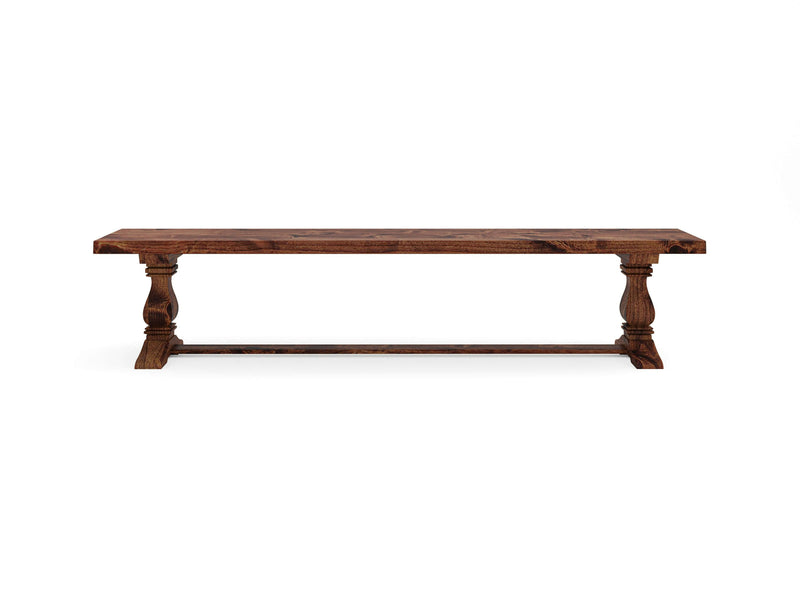 The Heirloom Bench - Tuscany by James+James is a rustic wooden dining table featuring a rectangular top and elegantly carved legs connected by a horizontal support beam at the base, all finished in a warm, natural wood tone.