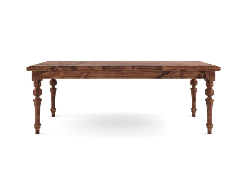 The Allyson Dining Table - Tuscany by James+James is a wooden dining table with a rectangular top and intricately carved legs. It boasts a rich, medium-brown finish that highlights the wood grain. The legs feature decorative turning, adding an antique charm to the overall design.