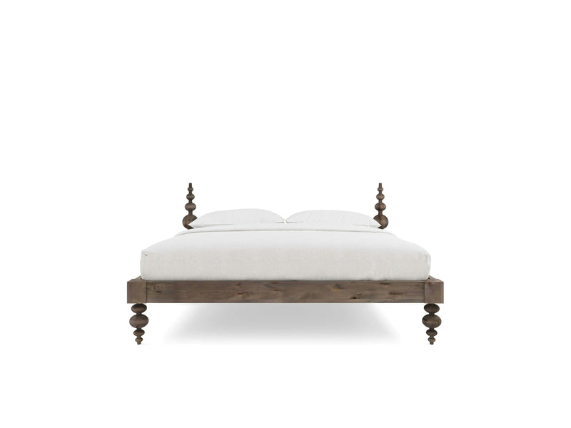 The Ophelia Bed - Barn Wood by James+James features distinctive spindle posts at each corner, adding a traditional touch to its design. The wooden bed comes with a light-colored mattress and two pillows, showcasing clean lines and a minimalist look that make it both elegant and functional.