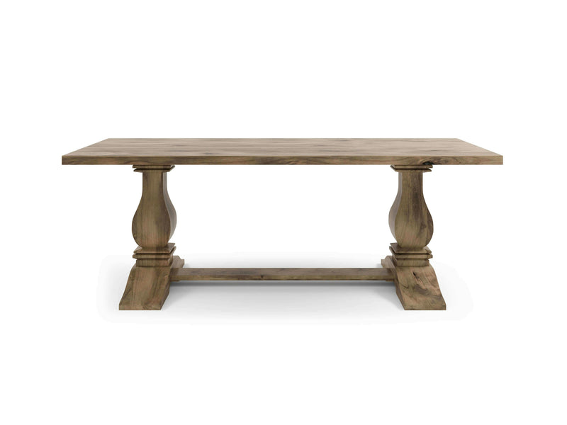 The Heirloom Dining Table - Harvest Wheat by James+James is a rectangular wooden table with a rustic finish. It features a plank-style top and two ornate pedestal legs connected by a horizontal support beam at the base. The design is simple yet elegant, making it suitable for dining or living spaces.