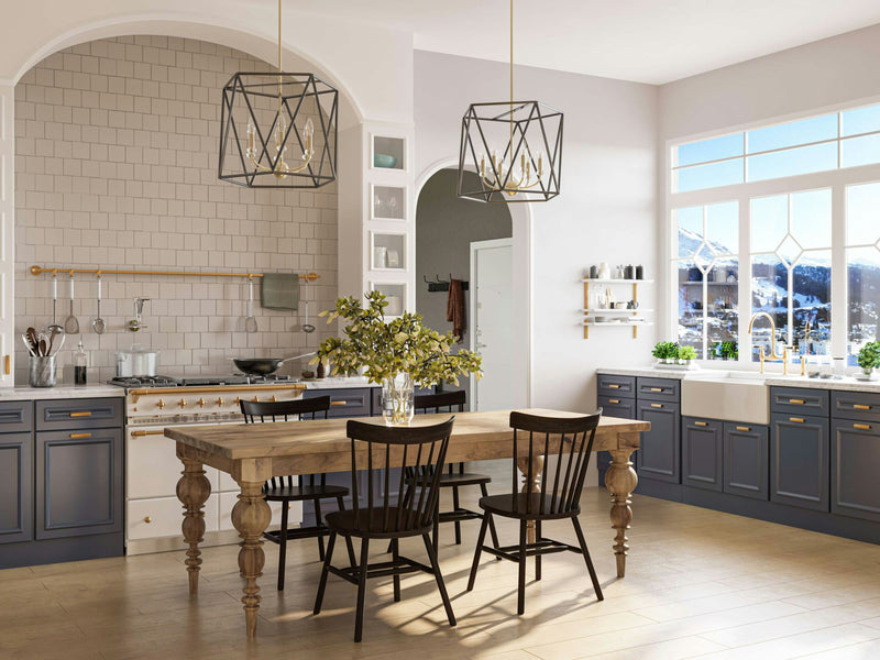 A modern kitchen with a rustic touch, featuring the Bailey Expandable Dining Table in Harvest Wheat by James+James surrounded by black chairs. The kitchen boasts blue cabinets, a white subway tile backsplash, and two geometric pendant lights. A large window offers a stunning view of snow-covered mountains outside.