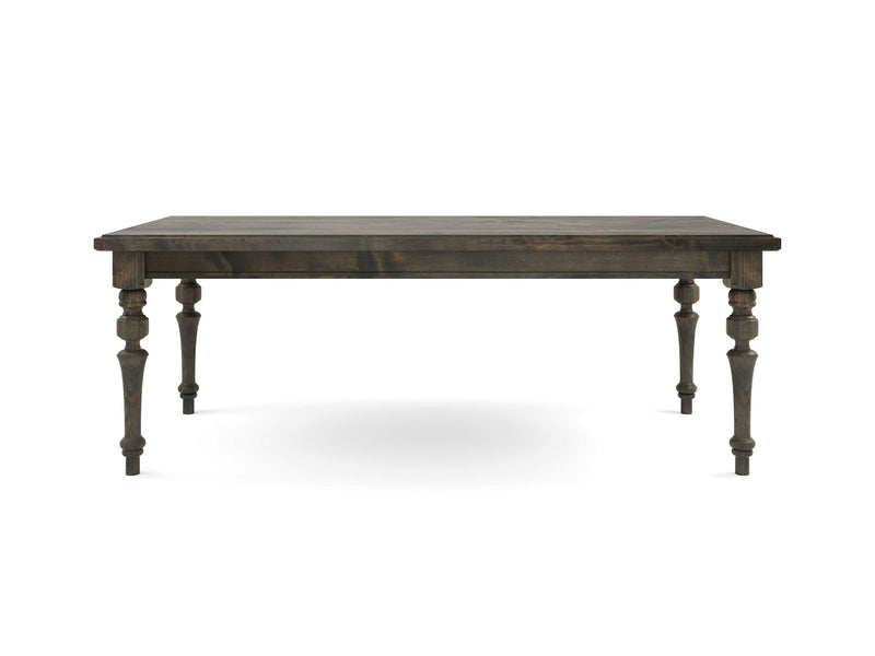 The Allyson Dining Table by James+James features a rustic, deep grey wood finish with a rectangular top and decorative turned legs. This table boasts a simple yet elegant design that highlights the natural wood grain and sturdy construction. It stands on four ornately carved legs that taper towards the bottom, adding to its timeless charm.