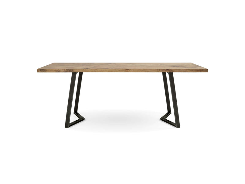 The Arkwright Dining Table - Harvest Wheat by James+James features a rectangular wooden tabletop with a smooth light brown finish. The table stands on black, angular metal legs that are slightly angled outwards and connect with horizontal supports near the floor, all set against a plain white studio background.