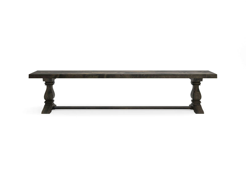 A long wooden Heirloom Bench - Deep Grey by James+James, featuring a rectangular top with a dark finish and natural wood grain pattern. The bench is supported by two ornate, carved legs connected by a horizontal stretcher bar near the base.