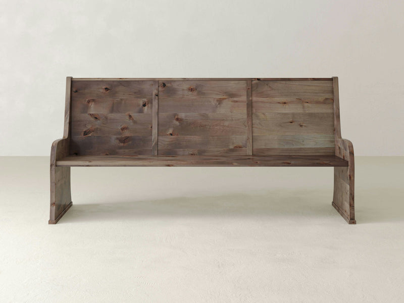 The Parish Pew Bench - Barn Wood by James+James is positioned against a light gray background. The bench showcases a rustic appearance, featuring a natural wood texture with visible knots and grains, and simple, sturdy construction.