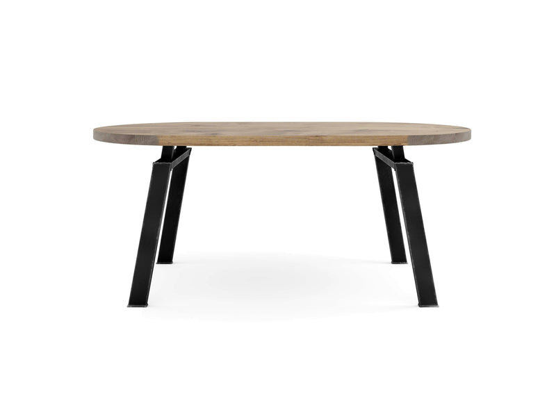 A round wooden table with a light brown top and four matte black metal legs, designed with an industrial aesthetic. The Fulton Oval Dining Table - Harvest Wheat by James+James is shown from the front angle, emphasizing its sturdy construction and modern style.